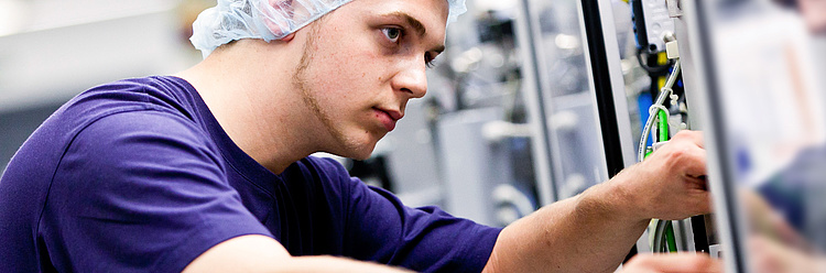 Ein Techniker in einem Haarnetz konzentriert sich auf die Wartung einer industriellen Maschine.