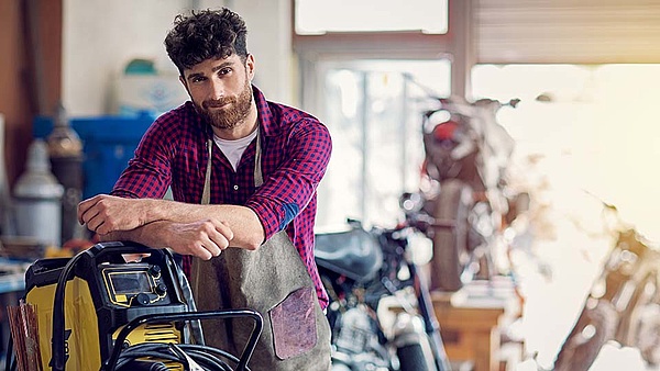 Ein Mechaniker steht in seiner Werkstatt vor Motorrädern