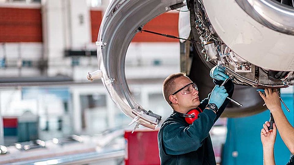 Ein Fluggerätemechaniker wartet mit seinem Kollegen eine Flugzeugturbine