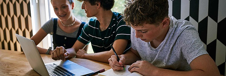 Drei Jugendliche sitzen vor einem Laptop.