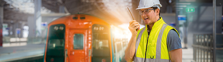 Mann mit Walkie Talkie bei der Arbeit im Schienenfahrzeugbau