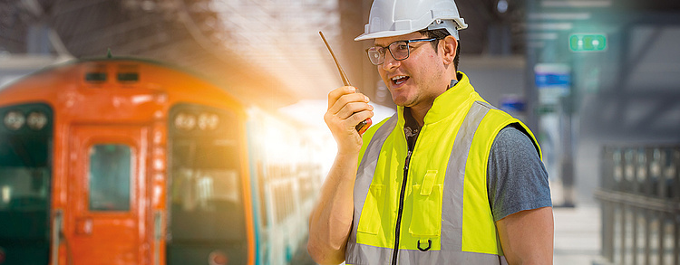 Mann mit Walkie Talkie bei der Arbeit im Schienenfahrzeugbau