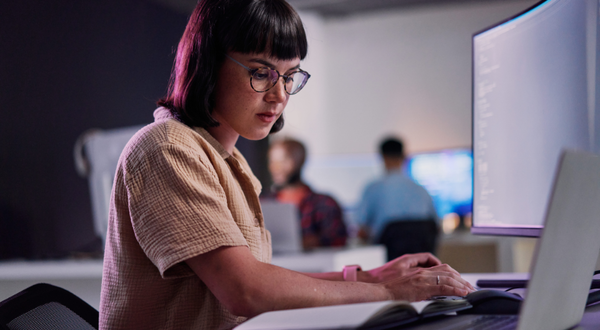 Fachinformatikerin mit Brille arbeitet konzentriert am Computer.