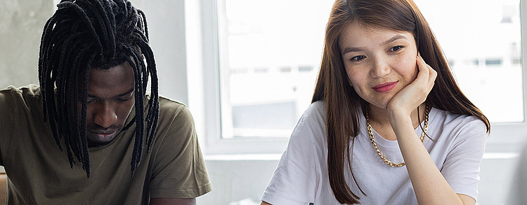 Studierende arbeiten gemeinsam an einem Projekt mit Büchern und Heften an einem Tisch.