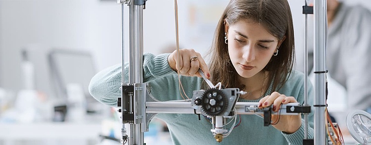 Auszubildende in einem MINT-Beruf justiert Bauteile.