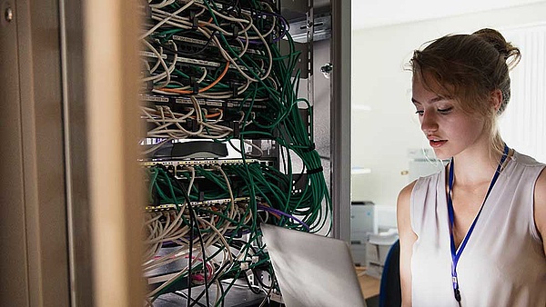 Eine Informatikerin arbeitet an der firmeninternen Netzwerkinfrastruktur