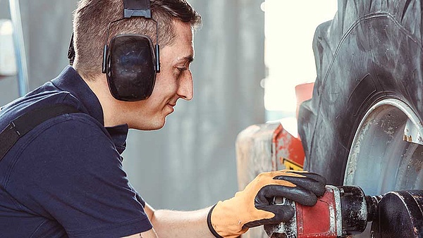 Ein Angestellter wechselt Reifen an einer Industriemaschine