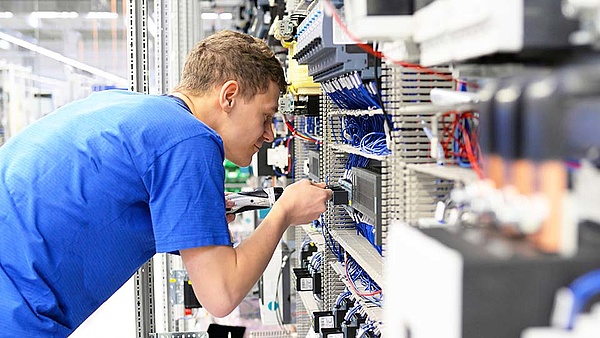 Ein Mitarbeiter arbeitet am Schaltschrank mit seinem Werkzeug