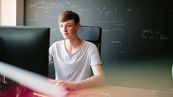 In einem Klassenzimmer sitzt ein Junge am Computer