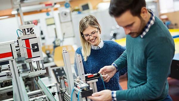 Zwei Angestellte stehen an einer Pneumatiksteuerung