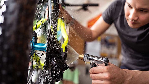 Ein Fahrradmonteur reinigt eine Gangschaltung in seiner Werkstatt