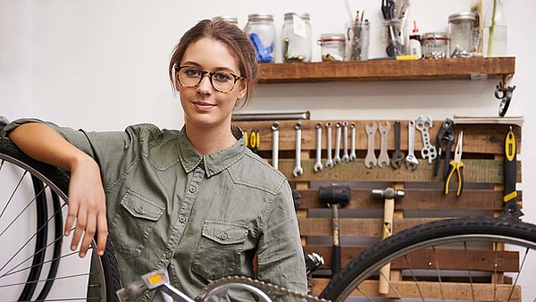 Eine Fahrradmonteurin steht in ihrer Werkstatt