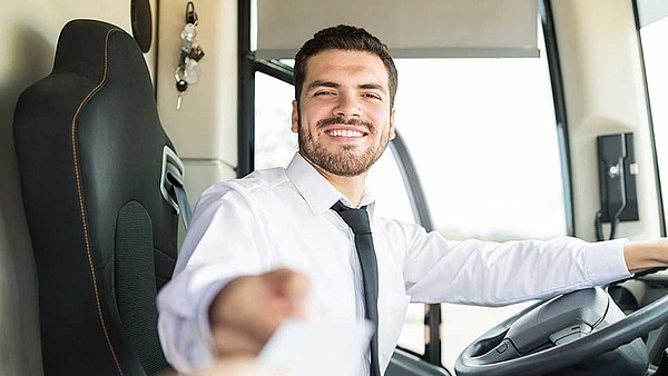 Ein Berufskraftfahrer lässt Passanten in seinen Bus einsteigen