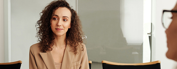 Geschäftsfrau in einem Meeting sitzt konzentriert zwischen Kollegen im Büro.