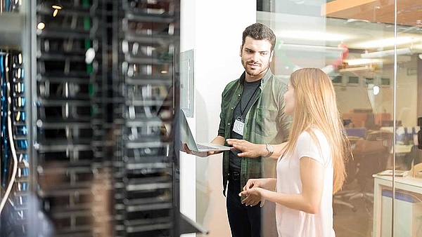 Ein Informatiker steht mit seiner Kollegin vor einem Rechenzentrum