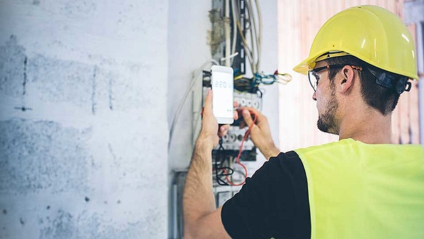 Ein Auszubildender überprüft Verkabelungen an einer Baustelle