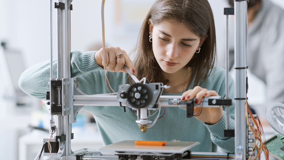 Auszubildende in einem MINT-Beruf justiert Bauteile.